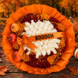Orange-wrapped bouquet of white roses and autumn mums with small pumpkins