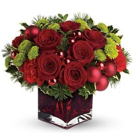 Red roses and green mums in a red glass vase with ornaments