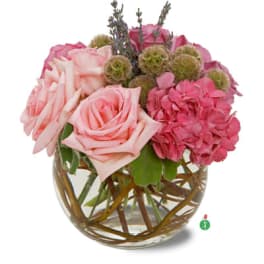 Short pink rose and hydrangea arrangement in a round glass vase