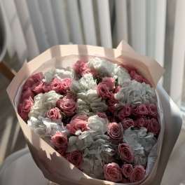 Bouquet of pink roses and white hydrangeas wrapped in pale pink paper