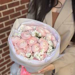 Bouquet of pale pink ranunculus with white filler flowers in paper wrap