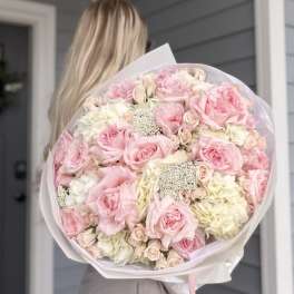 Large bouquet of pink and white roses wrapped in pale paper
