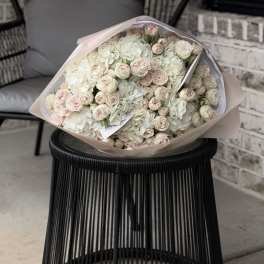 Large bouquet of pale pink and white roses wrapped in blush paper