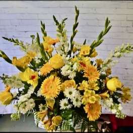 Large yellow and white floral arrangement with tall stems in a basket
