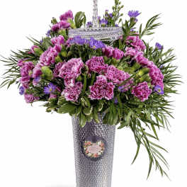Purple carnations and daisies in a tall silver vase