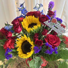 Basket arrangement with red roses, sunflowers, and purple flowers
