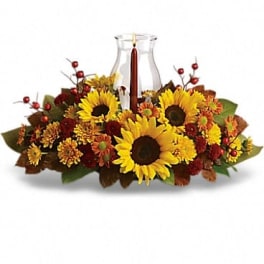 Sunflower and autumn floral centerpiece around a glass hurricane vase