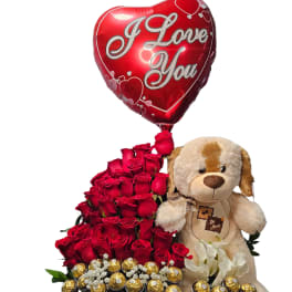 Red rose arrangement with a heart balloon, teddy bear, and chocolates in a basket