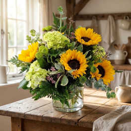 Sunflower and green hydrangea arrangement in a clear glass vase