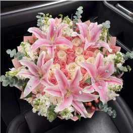 Pink lilies and roses arranged in a bouquet with white accents