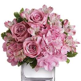 Pink roses and hydrangeas arranged in a clear square vase