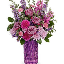 Pink and purple mixed flower arrangement in a purple vase