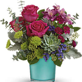 Pink roses and purple flowers in a turquoise glass vase