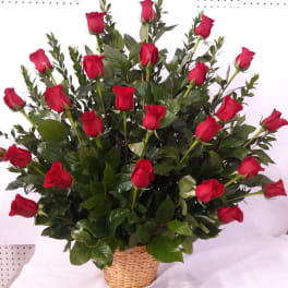Basket arrangement of red roses with glossy greenery