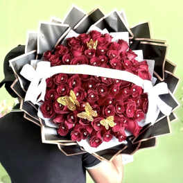 Large bouquet of deep red roses with black wrapping and white ribbon