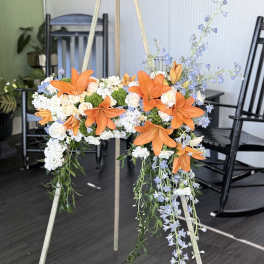 Orange lilies and white flowers arranged on a standing easel