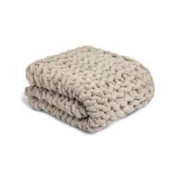 Folded beige chunky knit blanket on a white background