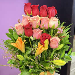 Basket arrangement of red and pink roses with orange lilies