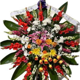 Large standing floral tribute with red, white, yellow, and pink flowers