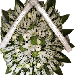 White floral standing spray with lilies, daisies, and green hydrangeas