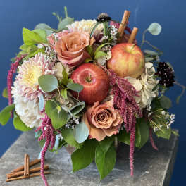 Mixed bouquet with roses, chrysanthemums, and apples on a stone pedestal
