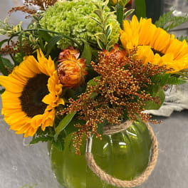 Sunflower arrangement in a green glass pumpkin vase with rope handle