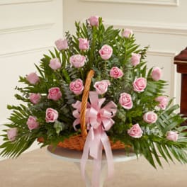 Basket arrangement of pink roses with a pink ribbon bow