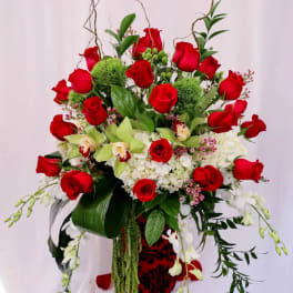 Tall bouquet of red roses, white orchids, and white hydrangeas in a decorative vase