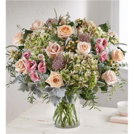 Bouquet of peach and pink roses with hydrangeas in a clear glass vase