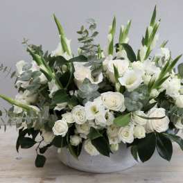 White floral arrangement in a low gray bowl with green accents