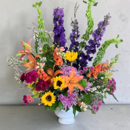 Colorful mixed flower arrangement in a white vase with tall purple spikes