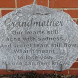 Gray memorial stone with an engraved poem against a brick wall