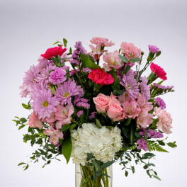 Mixed pink and white flowers arranged in a clear glass vase