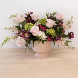 Pink and purple flower arrangement in a blush pedestal vase