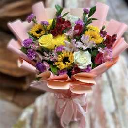 Bouquet of mixed flowers wrapped in pink paper with a ribbon