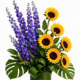 Sunflowers and purple delphinium in a clear glass vase