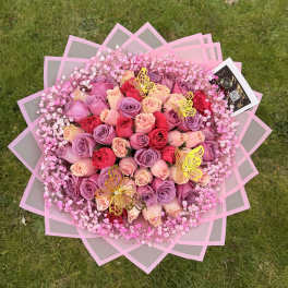 Large bouquet of pink, lavender, and red roses with baby’s breath