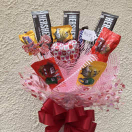 Candy bouquet with Hershey bars, M&M's, and a heart balloon in a glass vase