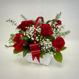 White basket of red roses and white filler flowers with a red handle and bow.