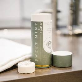 Mint + Lime scented candle in a green cylindrical container with a lid