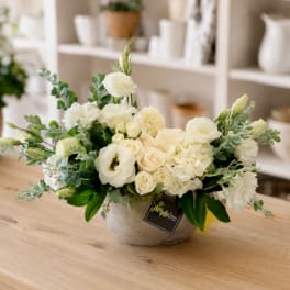 White floral arrangement in a gray bowl vase on a wooden table