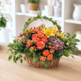 Basket arrangement with orange roses, yellow lilies, and purple hydrangeas