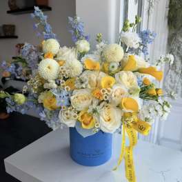 Blue and yellow mixed bouquet in a blue hat box with a ribbon