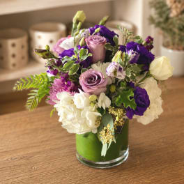 Mixed bouquet of purple, pink, and white flowers in a glass vase