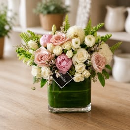 Pink and white flower arrangement in a square glass vase