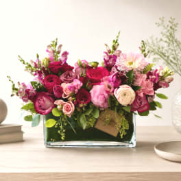 Pink and magenta flower arrangement in a rectangular glass vase