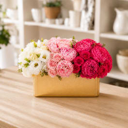 Pink and white flower arrangement in a gold rectangular vase