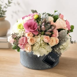 Pink and cream flower arrangement in a ribbed metal box
