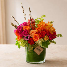 Bright mixed bouquet of roses and orchids in a glass vase