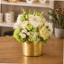 White and pale green floral arrangement in a gold container